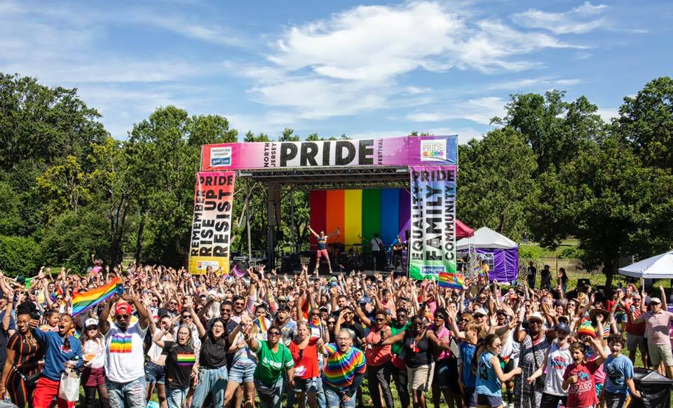 crowd of pride goers in front of stage under blue sky