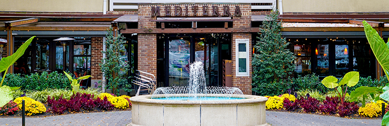 A courtyard with a fountain in front of a restaurant with a sign that reads "Mediterra", in Princeton, New Jersey