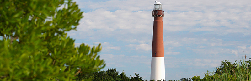 A white and red historic lighthouse, the Barnegat Lighthouse, in Barnegat Lighthouse State Park, in Barnegat New Jersey