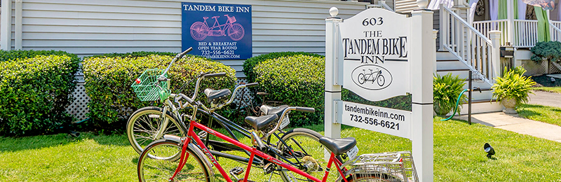Two bikes on the front lawn next to a sign reading "The Tandem Bike Inn", at the Tandem Bike Inn, in Belmar, New Jersey