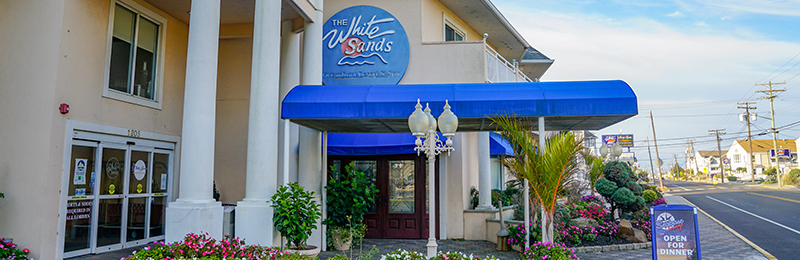 A tan building with a blue awning, with a circular sign reading "White Sands", in Point Pleasant, New Jersey