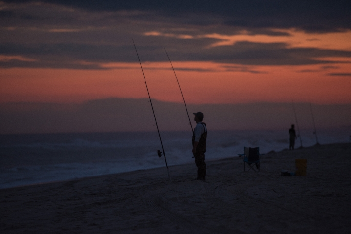 anglers casting for fish on the beach in sunset